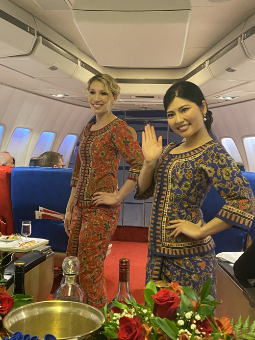two women in matching outfits standing in a plane
