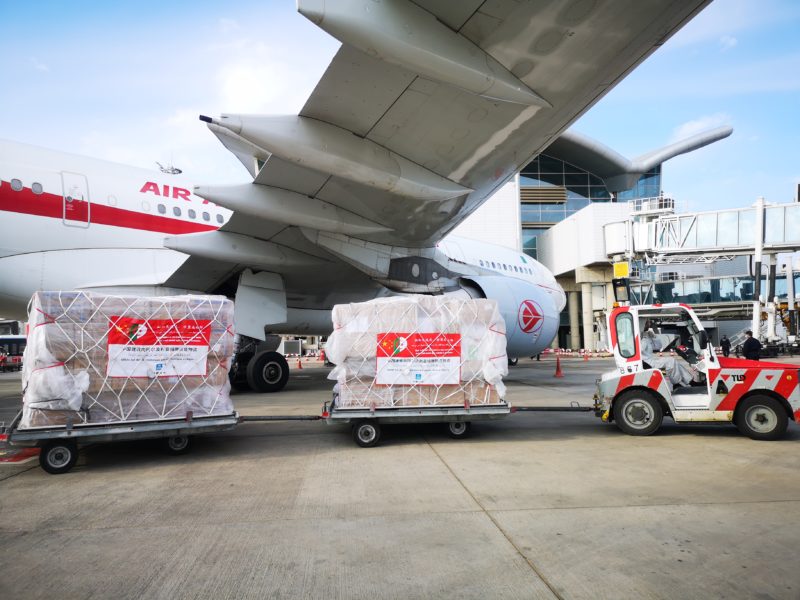 a large airplane with luggage carts and a forklift