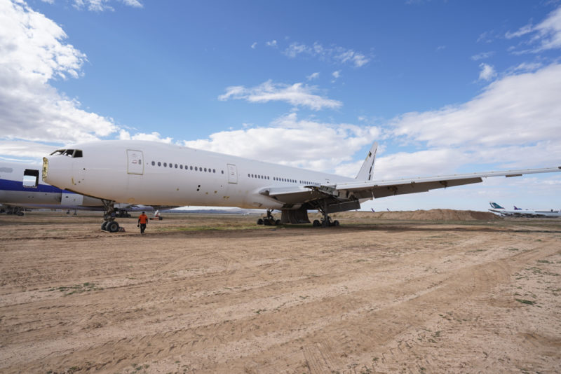 a large white airplane on a dirt field