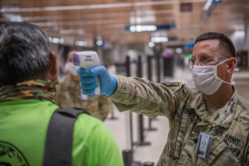 a soldier wearing a face mask and gloves pointing to a man