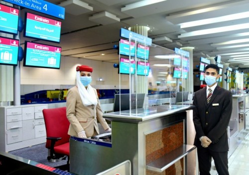 a man and woman wearing face masks standing in front of a counter