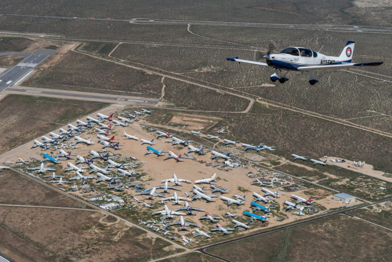 a plane flying over a field of airplanes