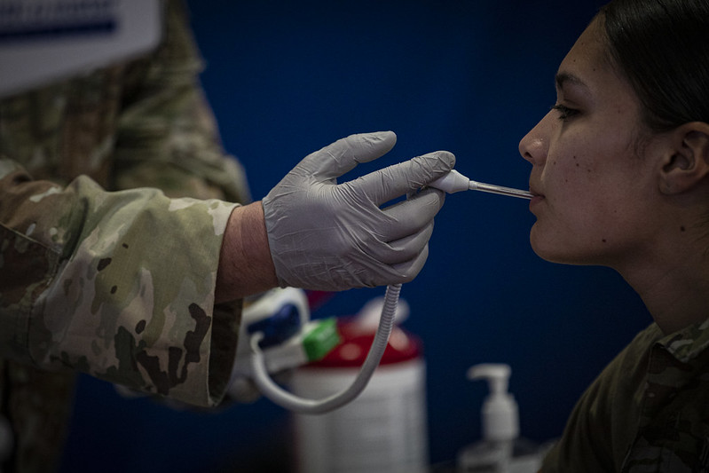 a person in uniform using a tool to check the mouth of a woman