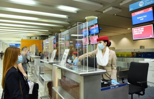 a woman wearing a mask and gloves at an airport check-in counter