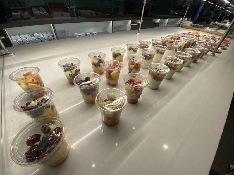 a row of plastic cups of fruit and cereals