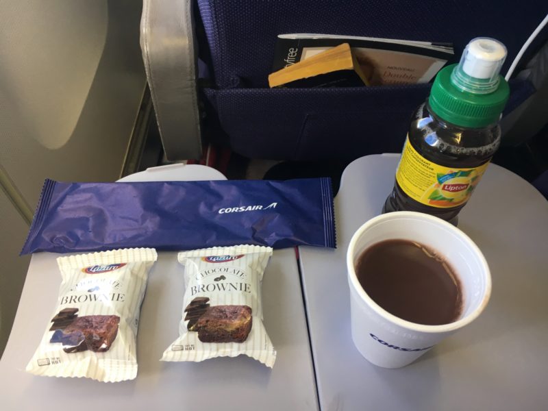 a cup of hot chocolate and some snacks on a plane