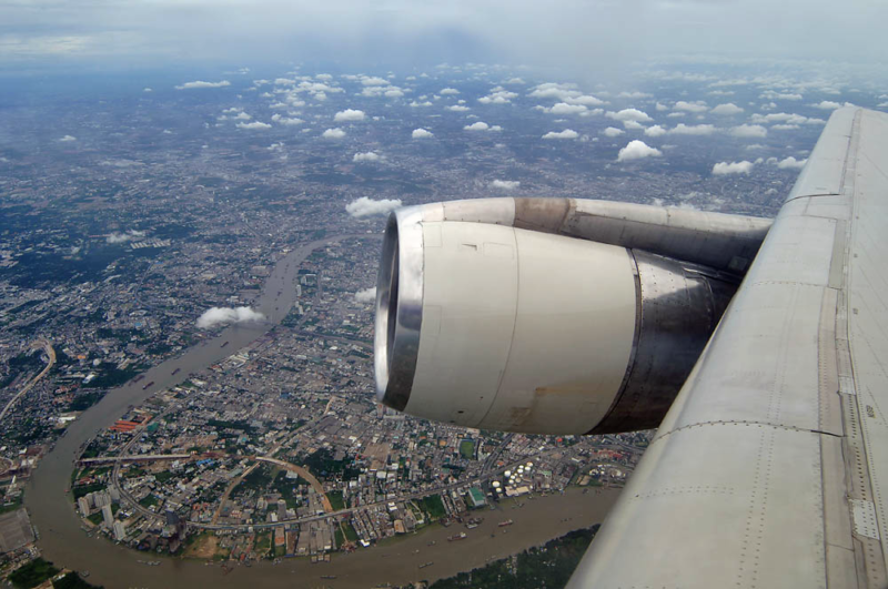 an airplane wing with a city and water below