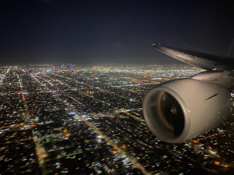 an airplane wing and wing of an airplane flying over a city at night