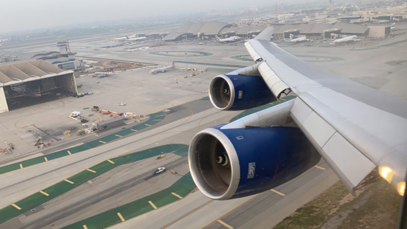 an airplane wing with blue engines and a runway