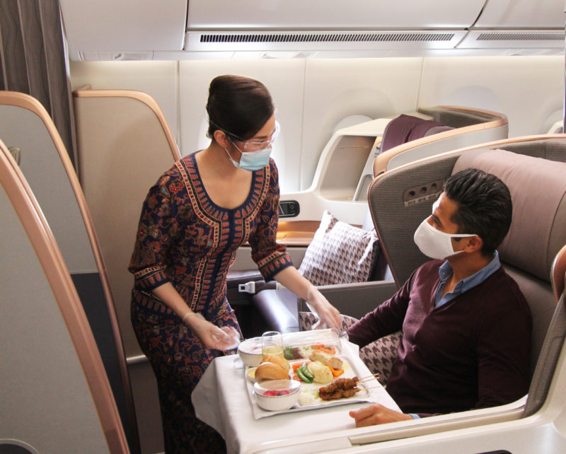 a woman serving food to a man on an airplane