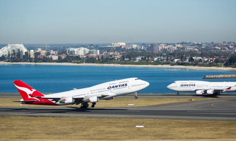 a two airplanes on a runway next to a body of water
