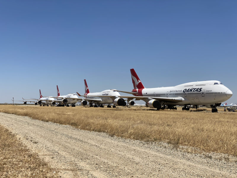 a group of airplanes parked on a dirt field