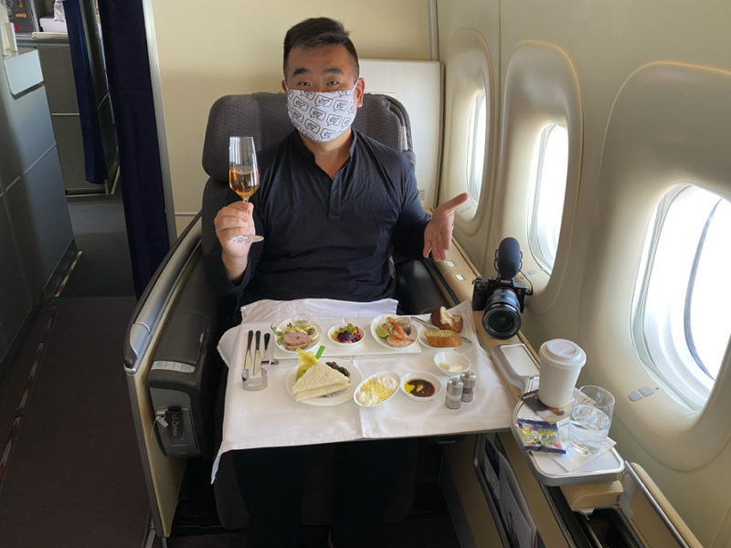 a man sitting in a chair with a face mask holding a glass of wine