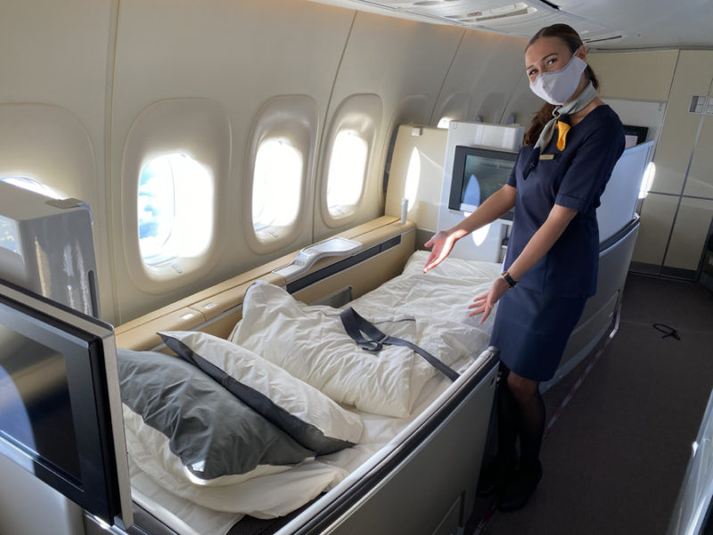 a woman wearing a mask standing next to a bed in an airplane