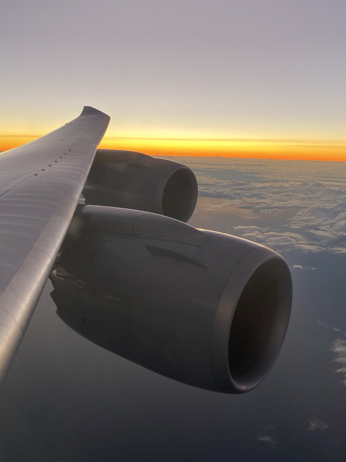 an airplane wing with clouds and orange sky