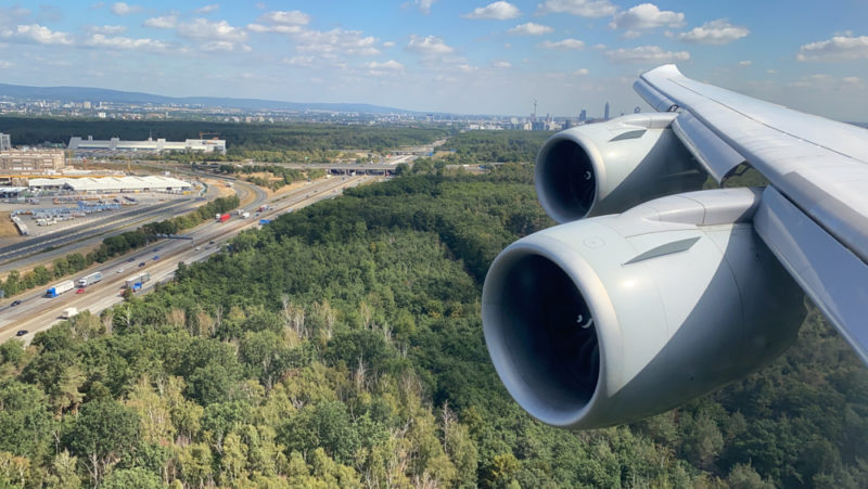 an airplane wing with a view of the city and trees