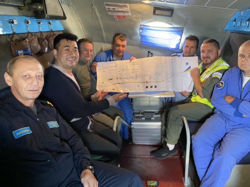a group of men in a plane holding a large piece of paper