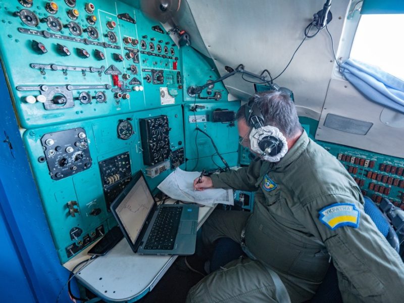 a man in a pilot's uniform working on a laptop