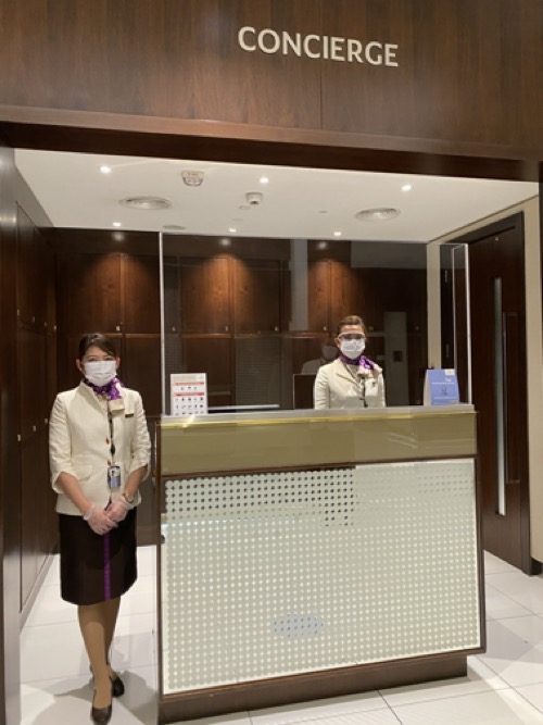 two women wearing face masks standing in front of a desk