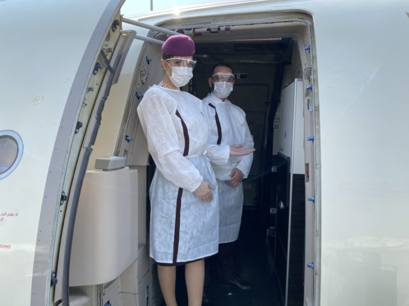 a couple of people wearing face masks and standing in an airplane