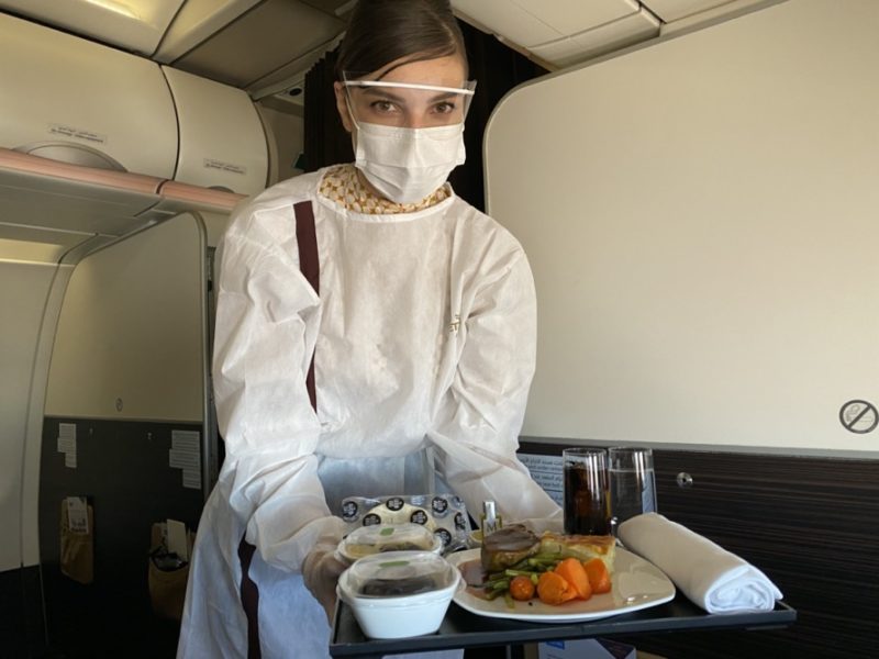 a person wearing a face mask and holding a tray of food