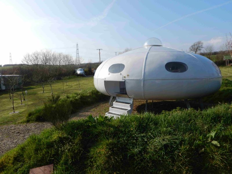 a white ufo shaped house in a grassy area