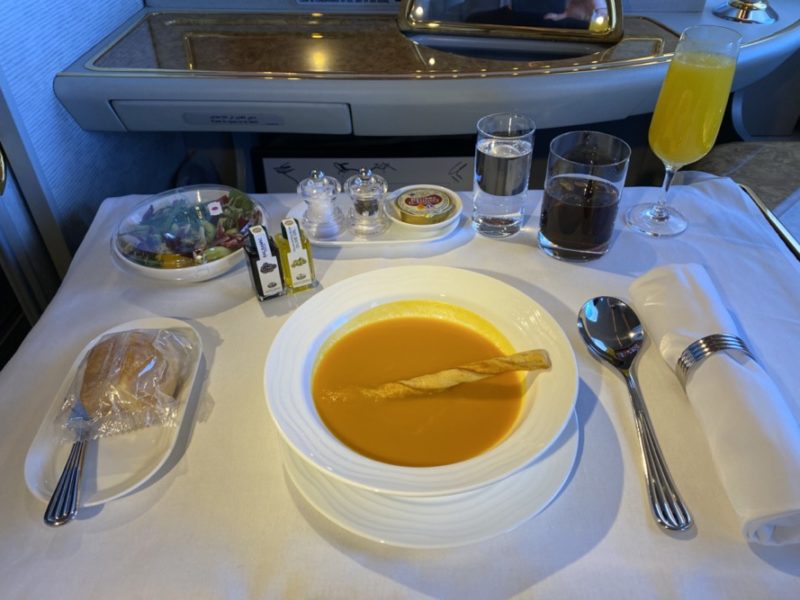 a bowl of soup and a glass of juice on a table