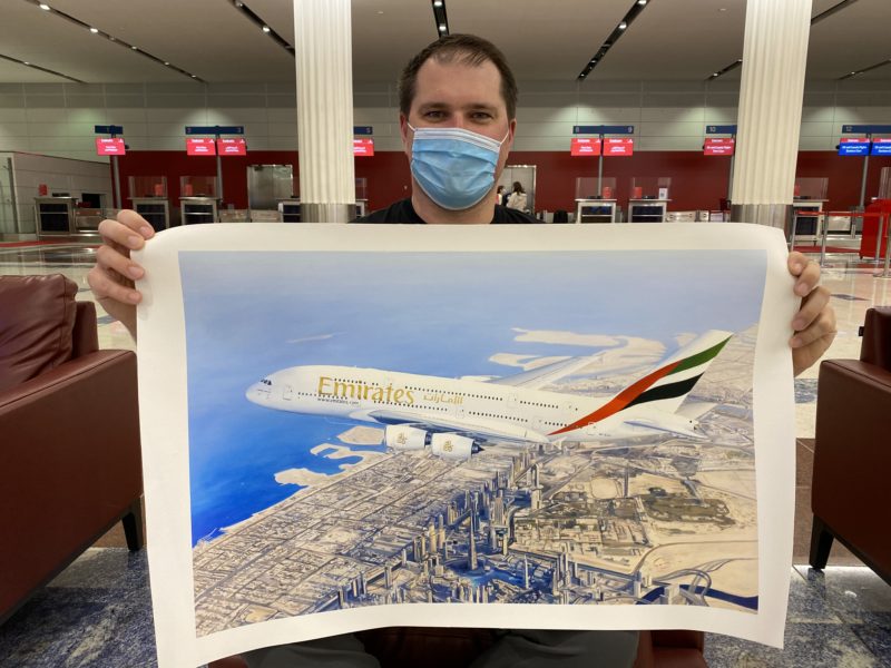 a man wearing a face mask holding a poster of an airplane