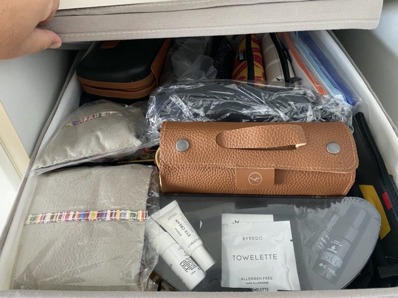 a hand opening a drawer with a brown leather purse and other items