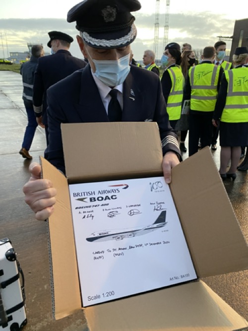 a man wearing a mask and holding a box with a plane in it