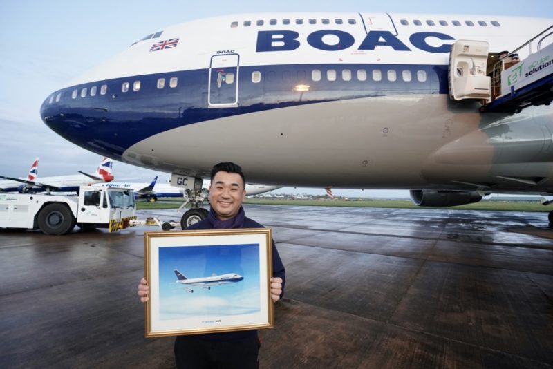 a man holding a picture in front of an airplane
