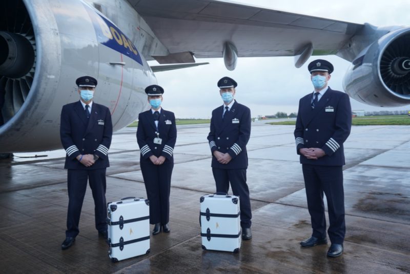 a group of people wearing masks and standing in front of an airplane