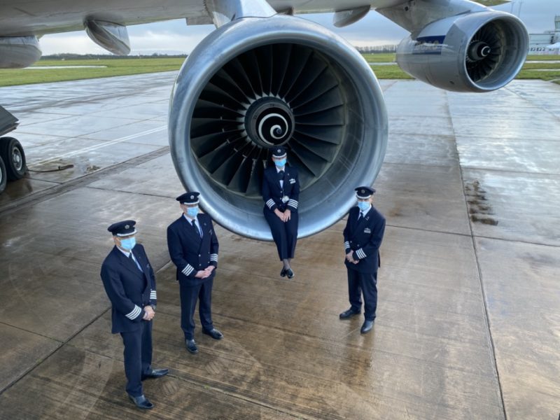 a group of people wearing face masks standing in front of an airplane