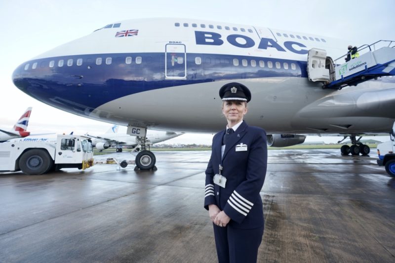 a woman in uniform standing in front of an airplane