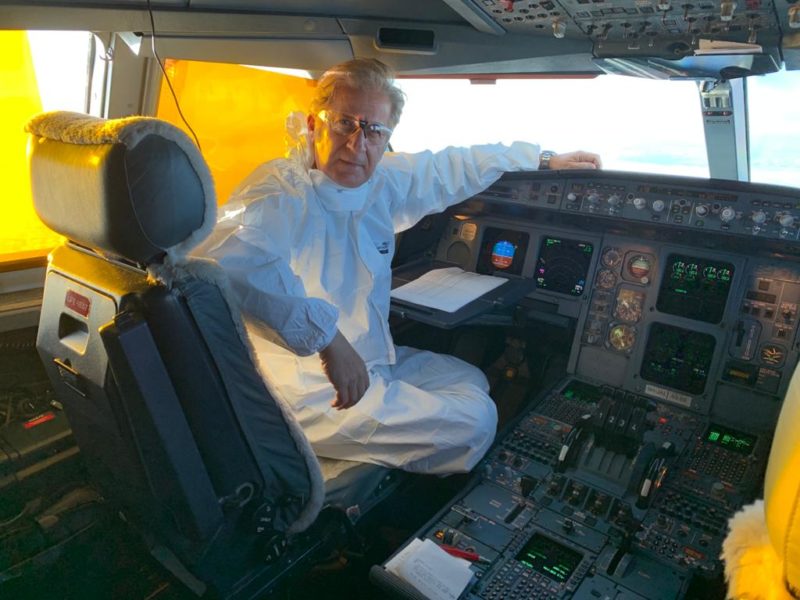 a man in a white suit sitting in a cockpit of an airplane