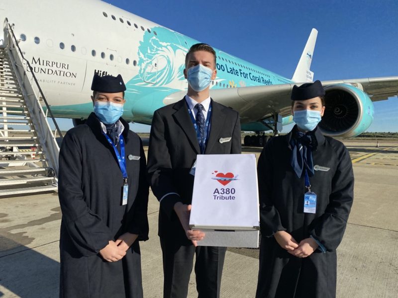 a group of people wearing face masks and standing in front of an airplane
