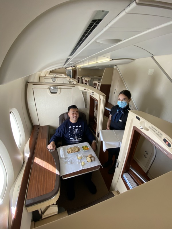 a man and woman sitting in a plane with a tray of food