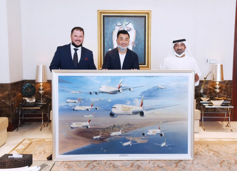 a group of men holding a large framed painting of airplanes