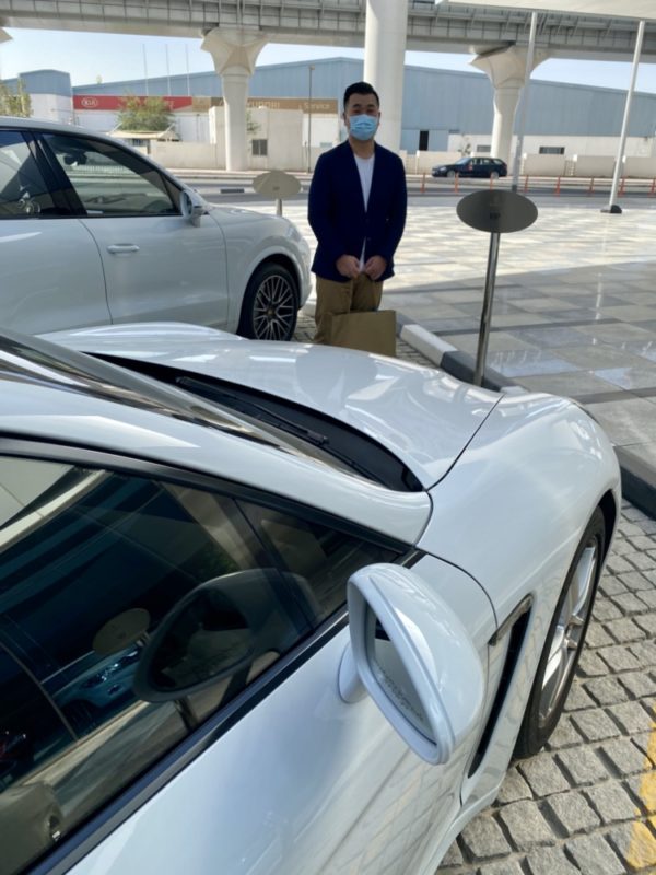a man wearing a face mask standing next to a white car