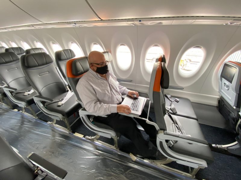 a man sitting in a plane with a laptop