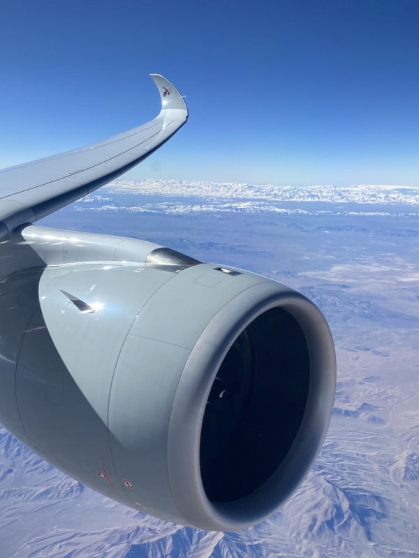 an airplane wing with a blue sky and snow covered mountains