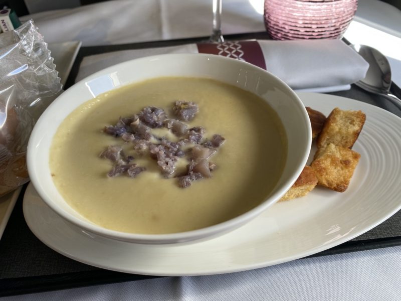 a bowl of soup with croutons on a plate