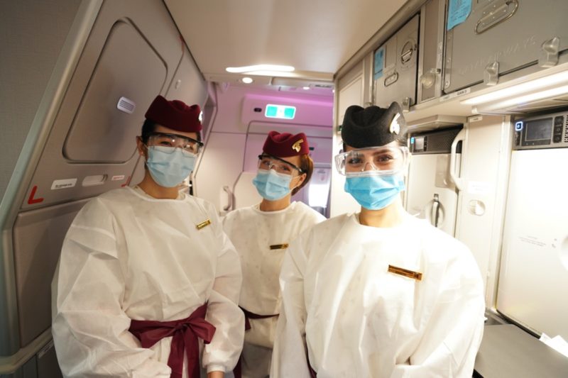 Qatar Airways Flight Attendant dressed in PPE with mask and visor