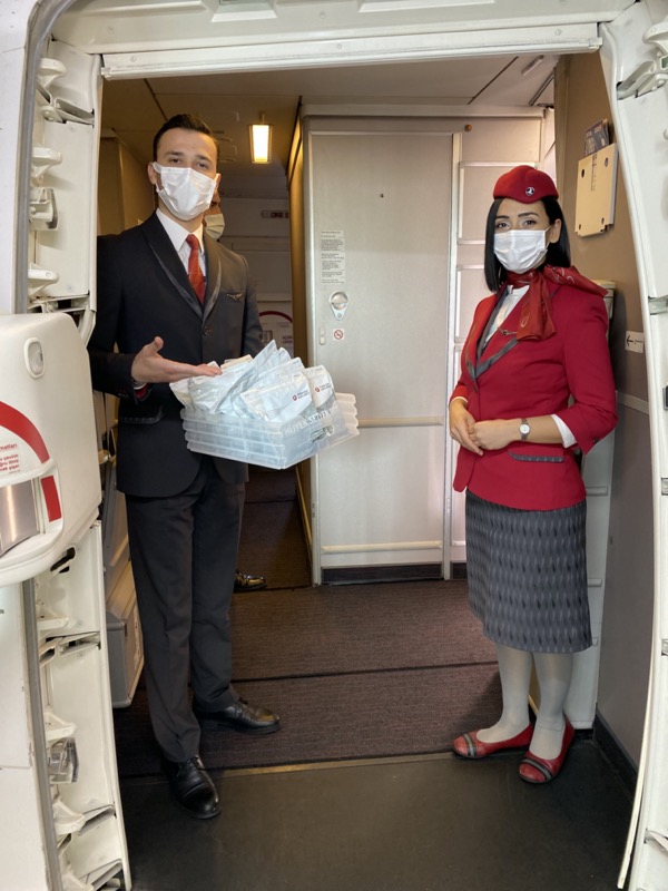 Turkish Airlines Flight Attendant welcome passenger with hygiene kit at the door