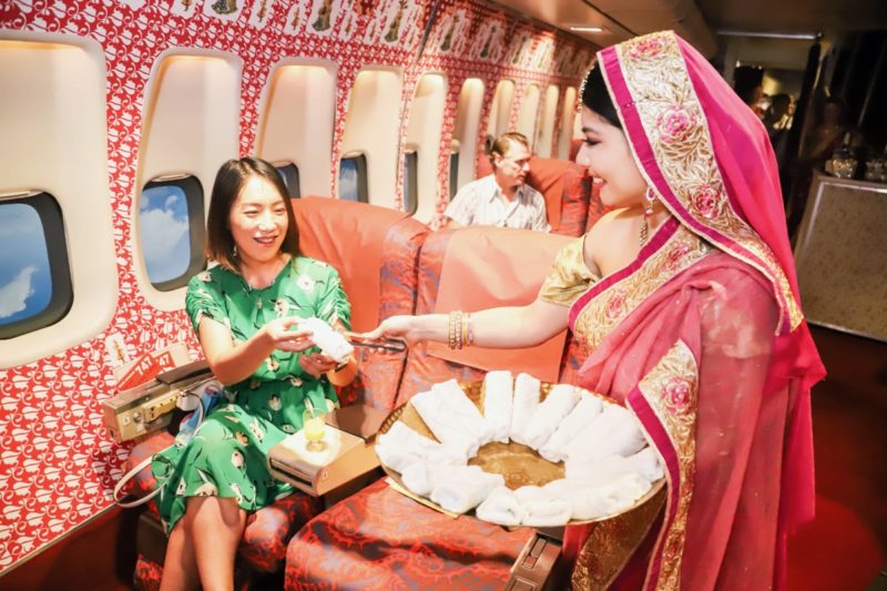 a woman in a sari giving a hand to a woman in a red and white airplane
