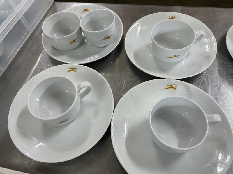 a group of white cups and saucers on a metal surface