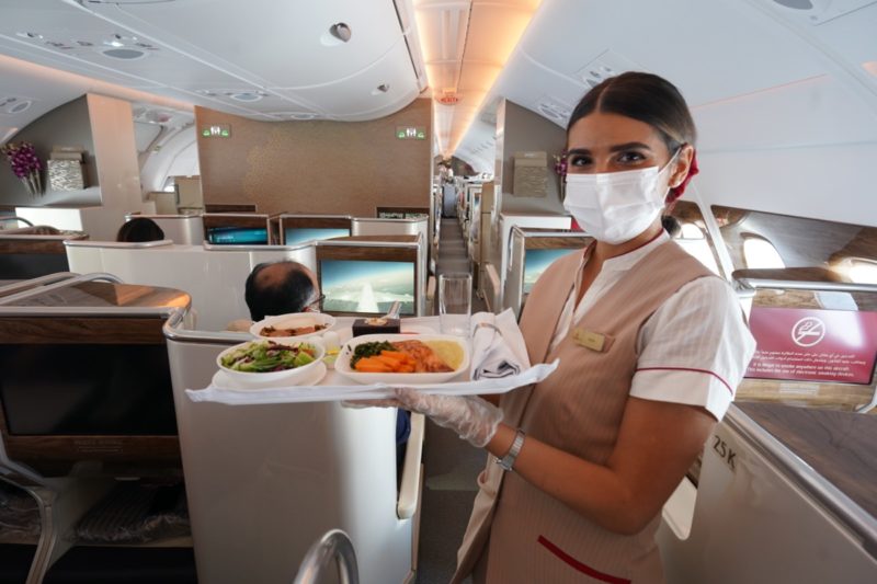 a woman wearing a mask and gloves holding a tray of food