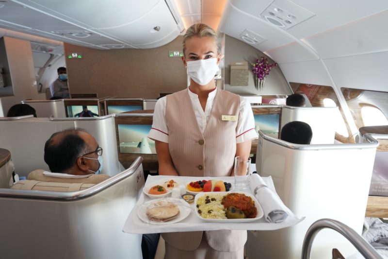 a woman wearing a mask holding a tray of food