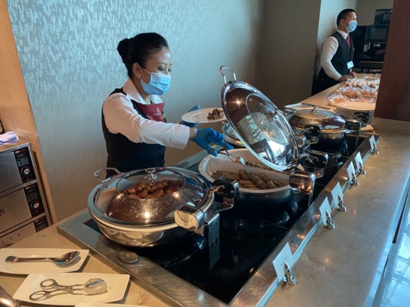 a woman wearing a face mask and gloves serving food