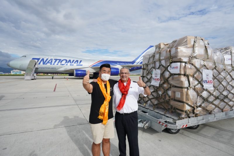 two men standing next to a large load of goods